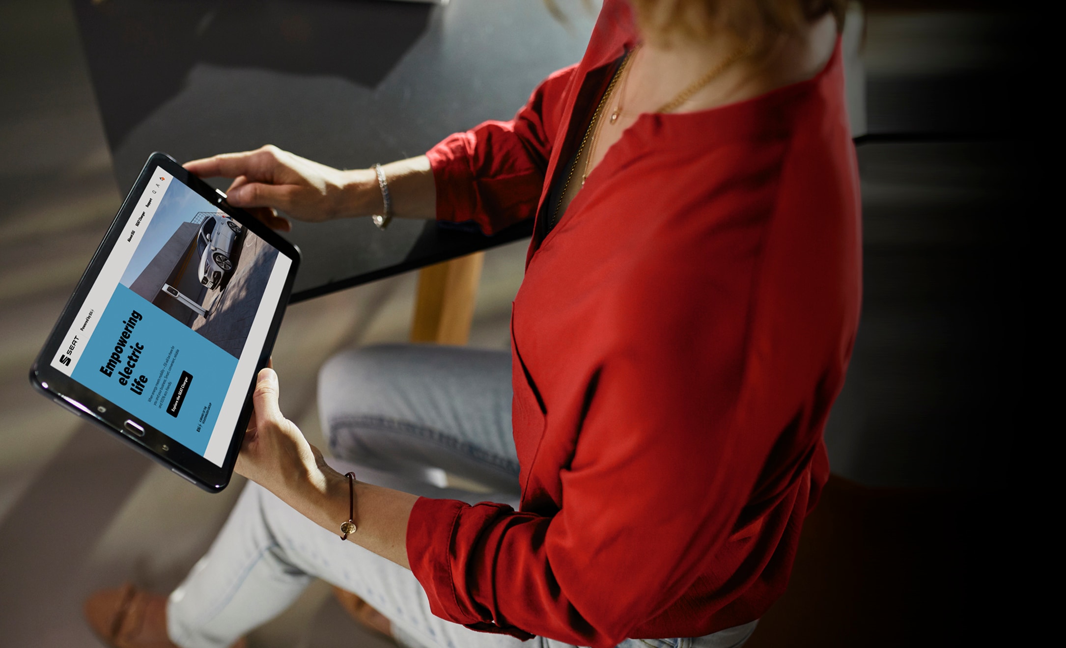 A woman viewing the SEAT website on an iPad, exploring the Empowering Electric Life section.