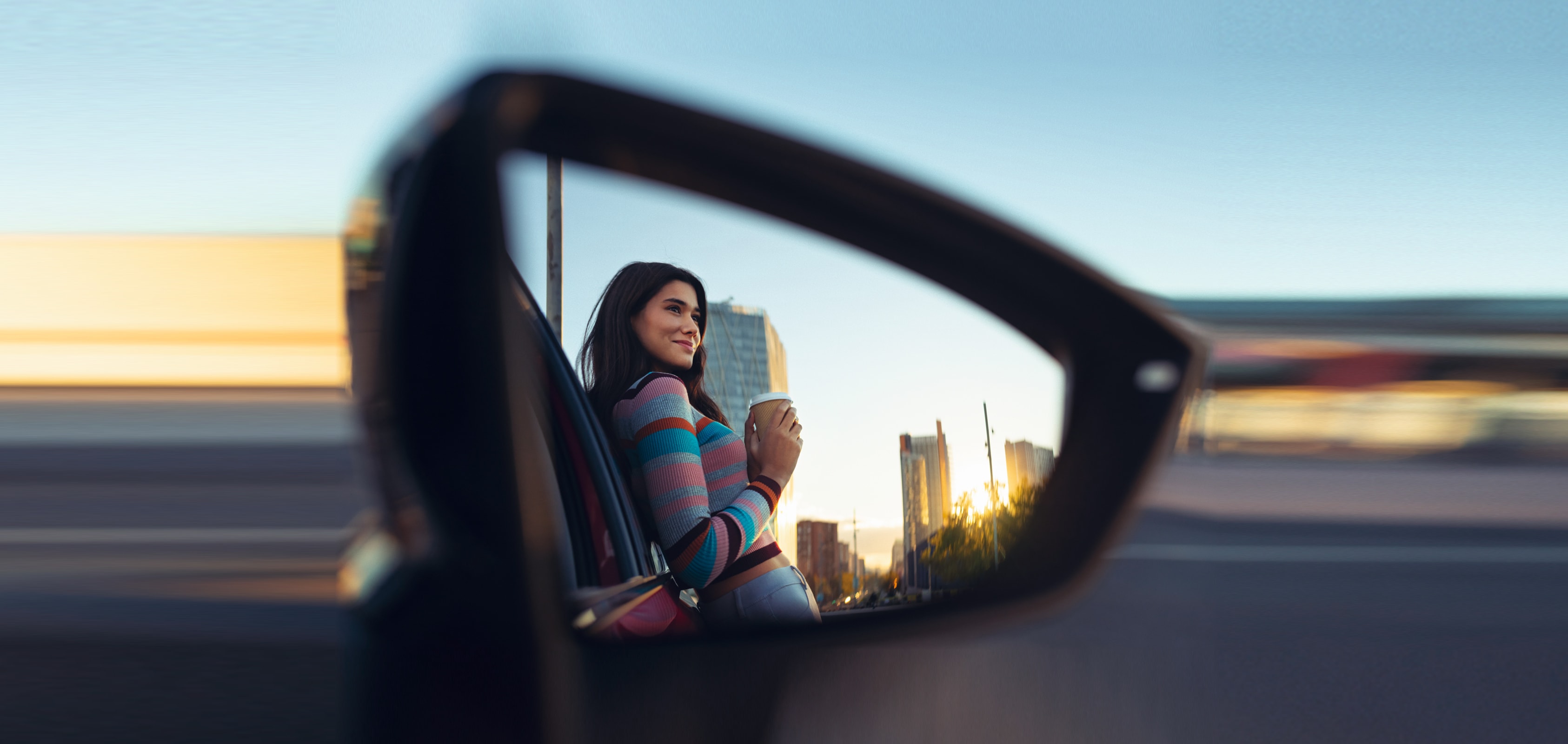 Woman leaning on a SEAT car drinking a coffee