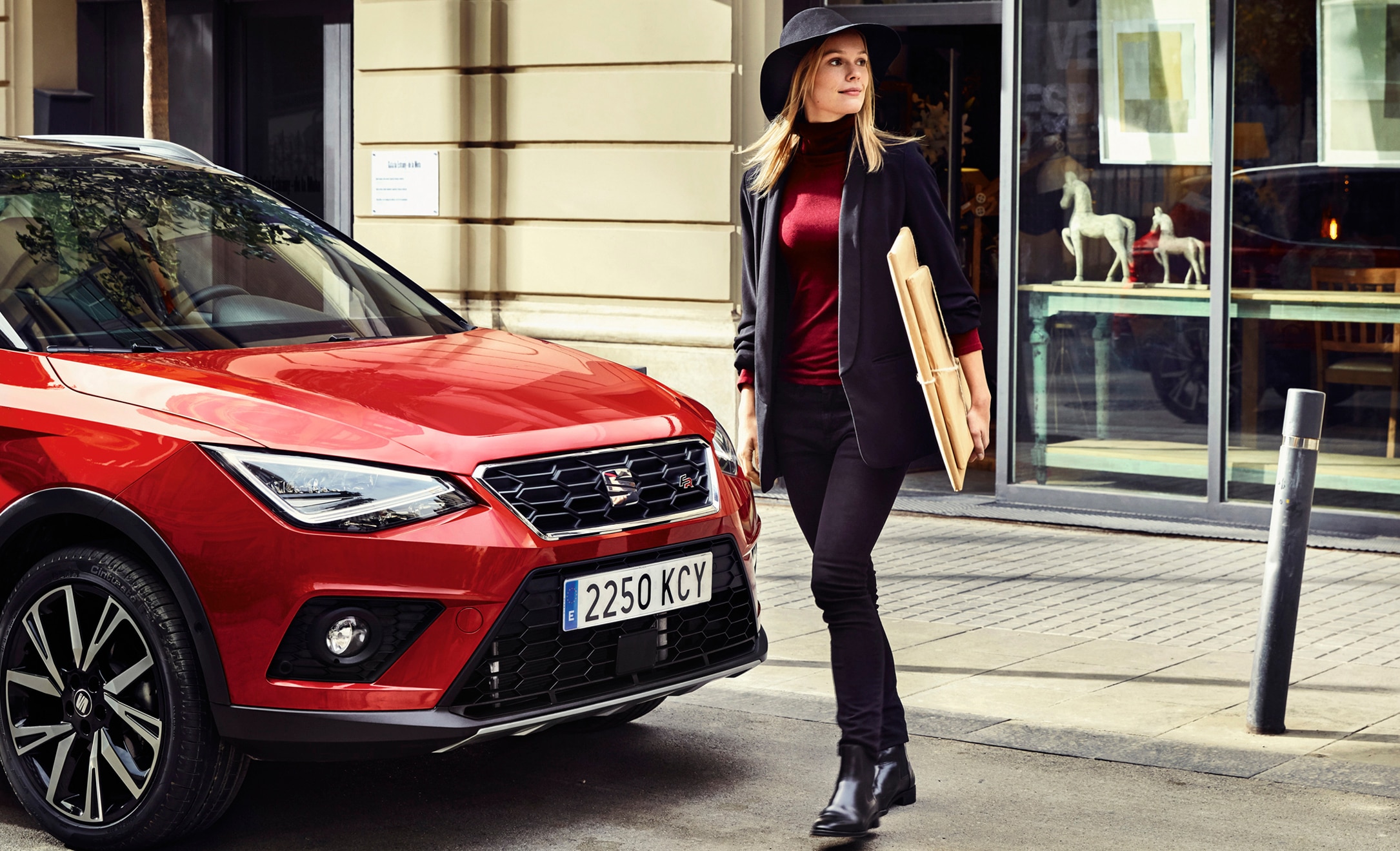 SEAT new car services and maintenance – Woman walking in front of a SEAT Arona crossover SUV