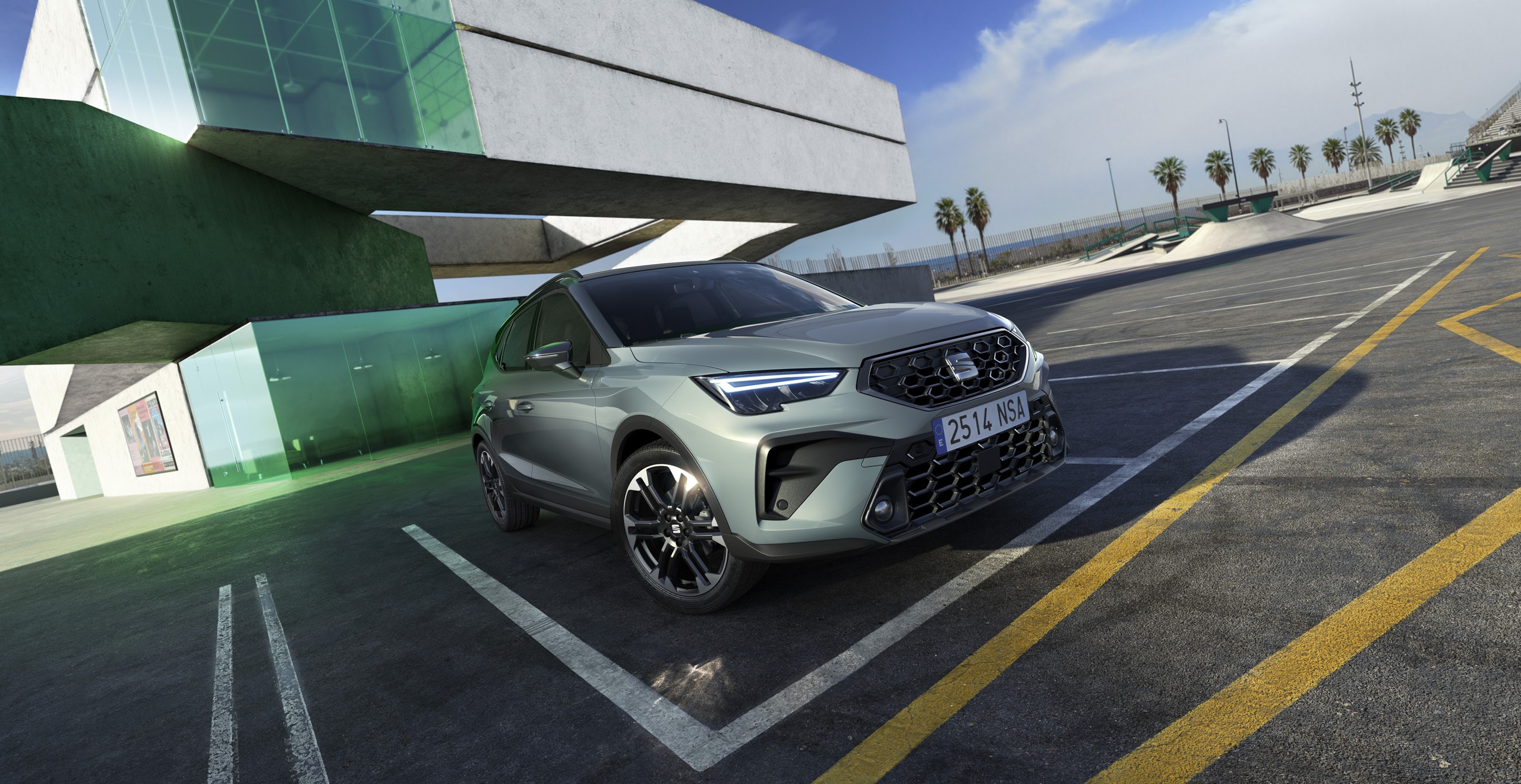 New SEAT Arona SUV in metallic grey parked under modern architecture, featuring bold grille, LED headlights, and sporty alloy wheels.