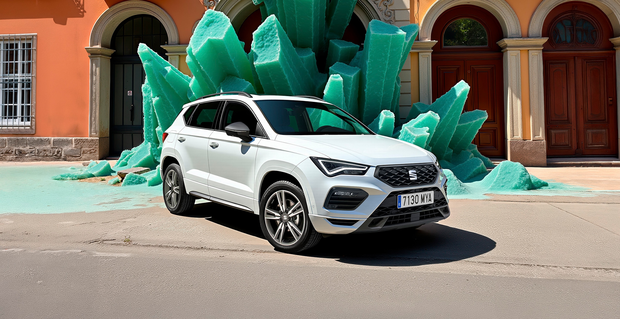 A white SEAT Ateca SUV parked on a street in front of an orange building with arched windows, with a large green stone structure resembling giant crystals behind it. 