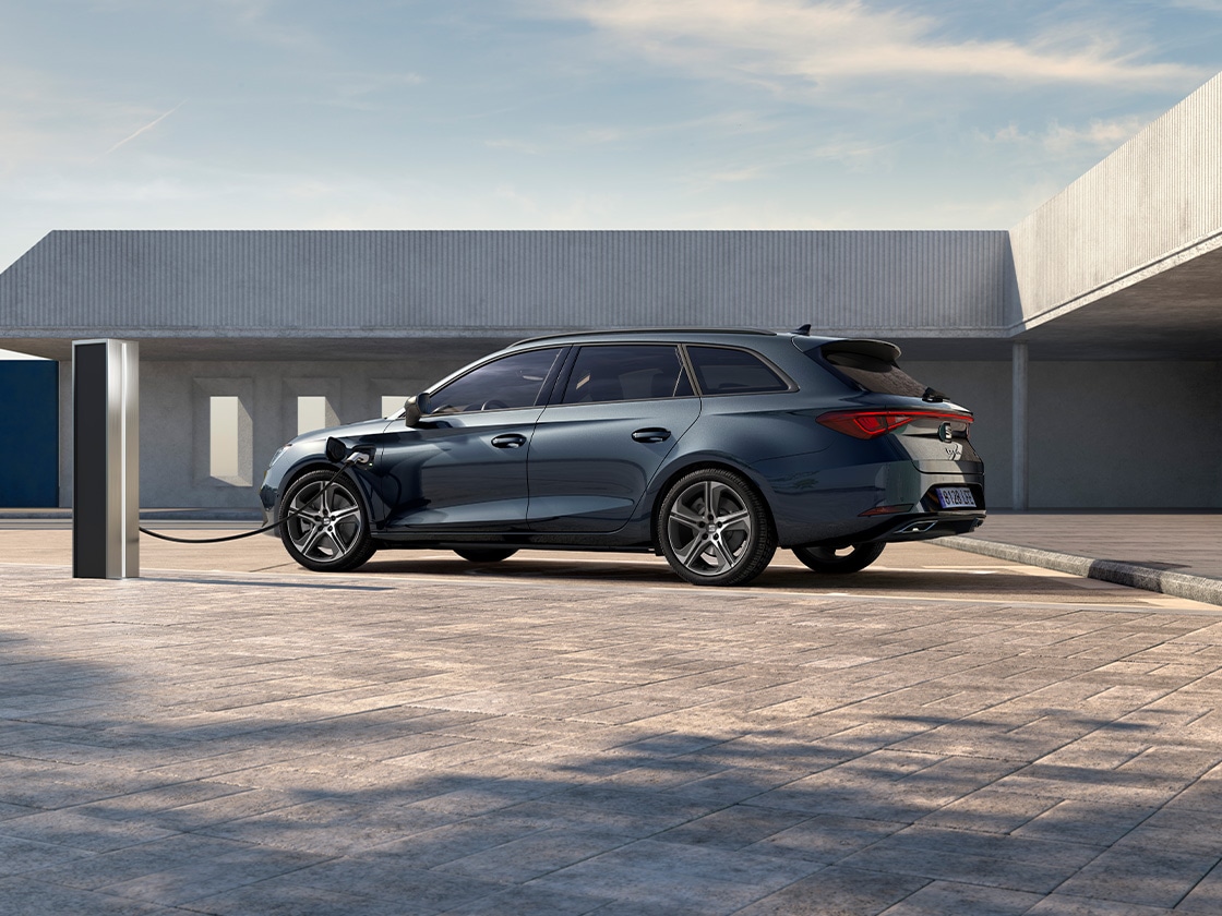 Seat leon sportstourer hatchback 2025 plug in hybrid electric vehicle and a seat charger. Parked and charging outdoors, featuring spoke alloy wheels, interior ambient lighting and heated front seats.
