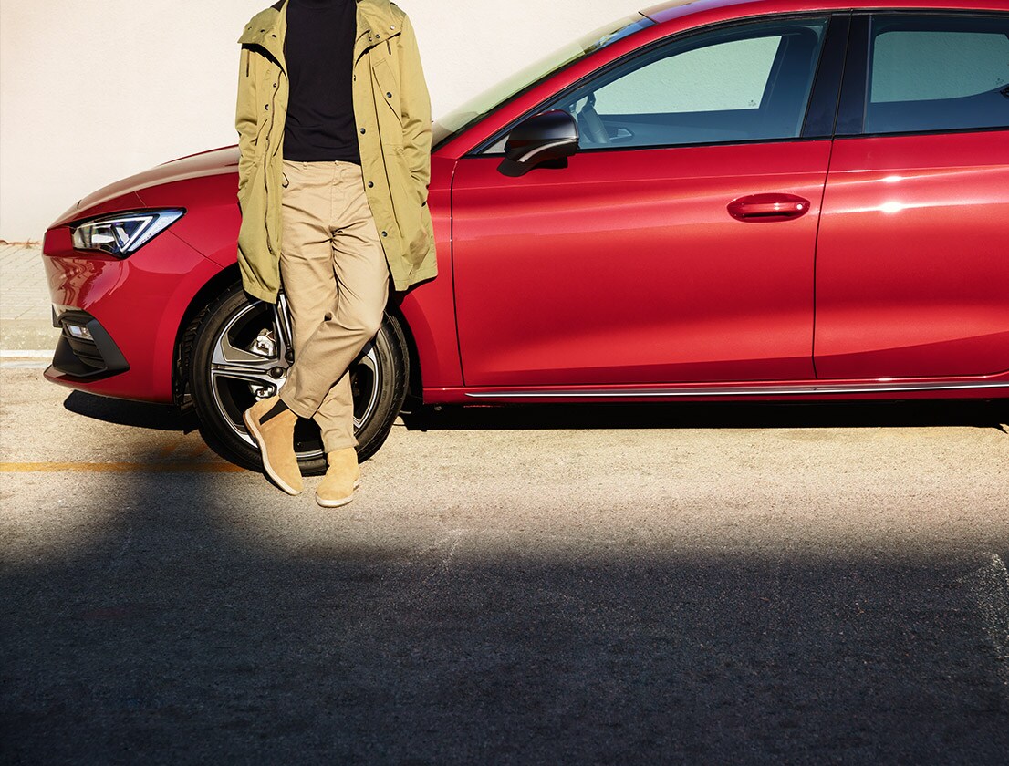 man standing next to seat leon sportstourer desire red colour
