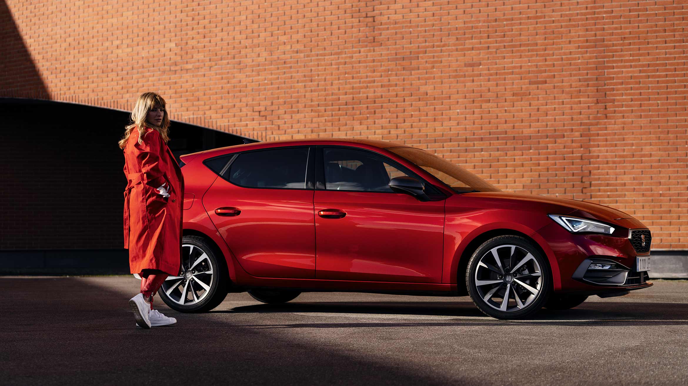 woman in a red coat standing next to seat leon desire red colour
