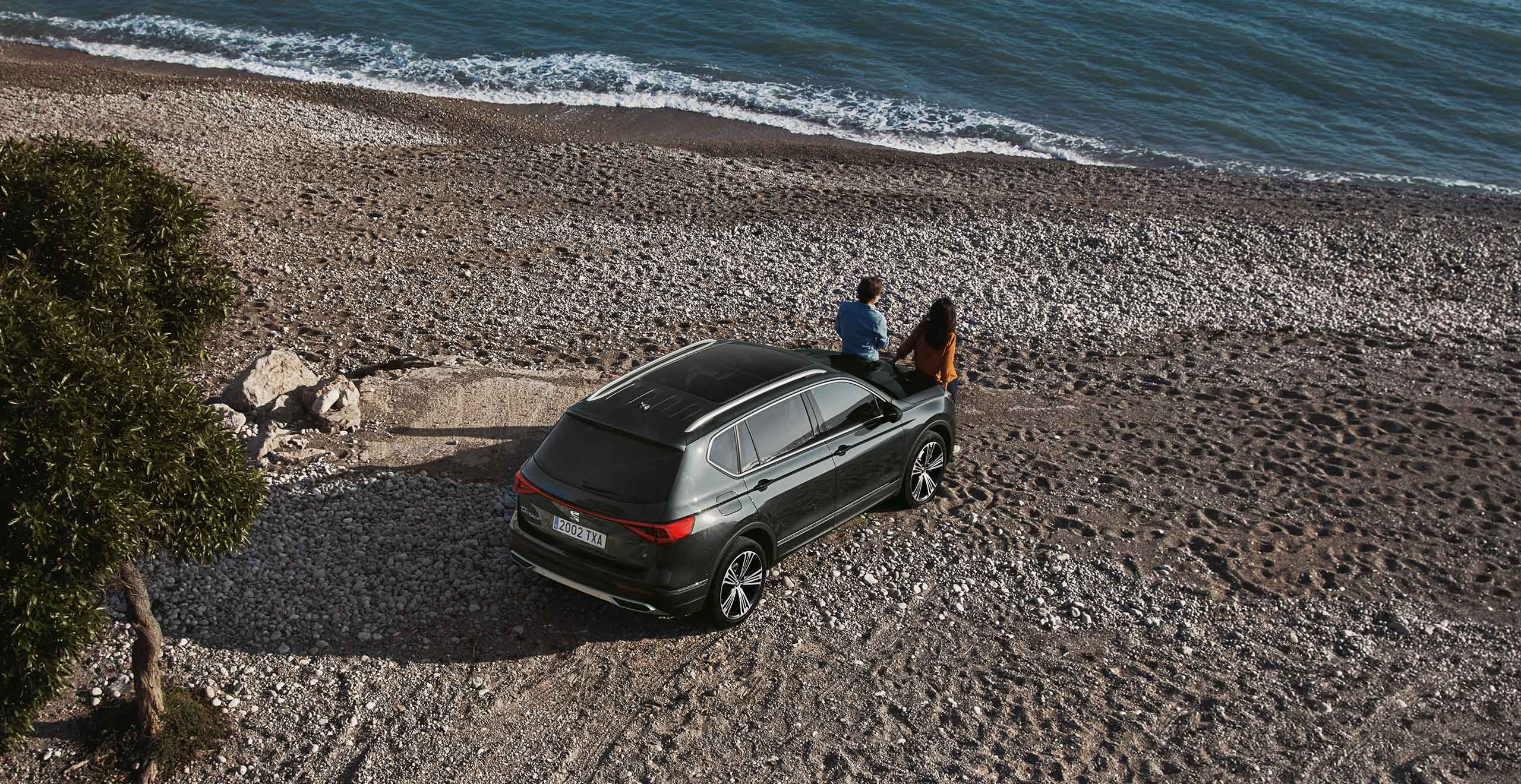 New SEAT Tarraco parked on beach with roadside assistance for fuel refill and dead battery maintenance couple in front of the Tarraco