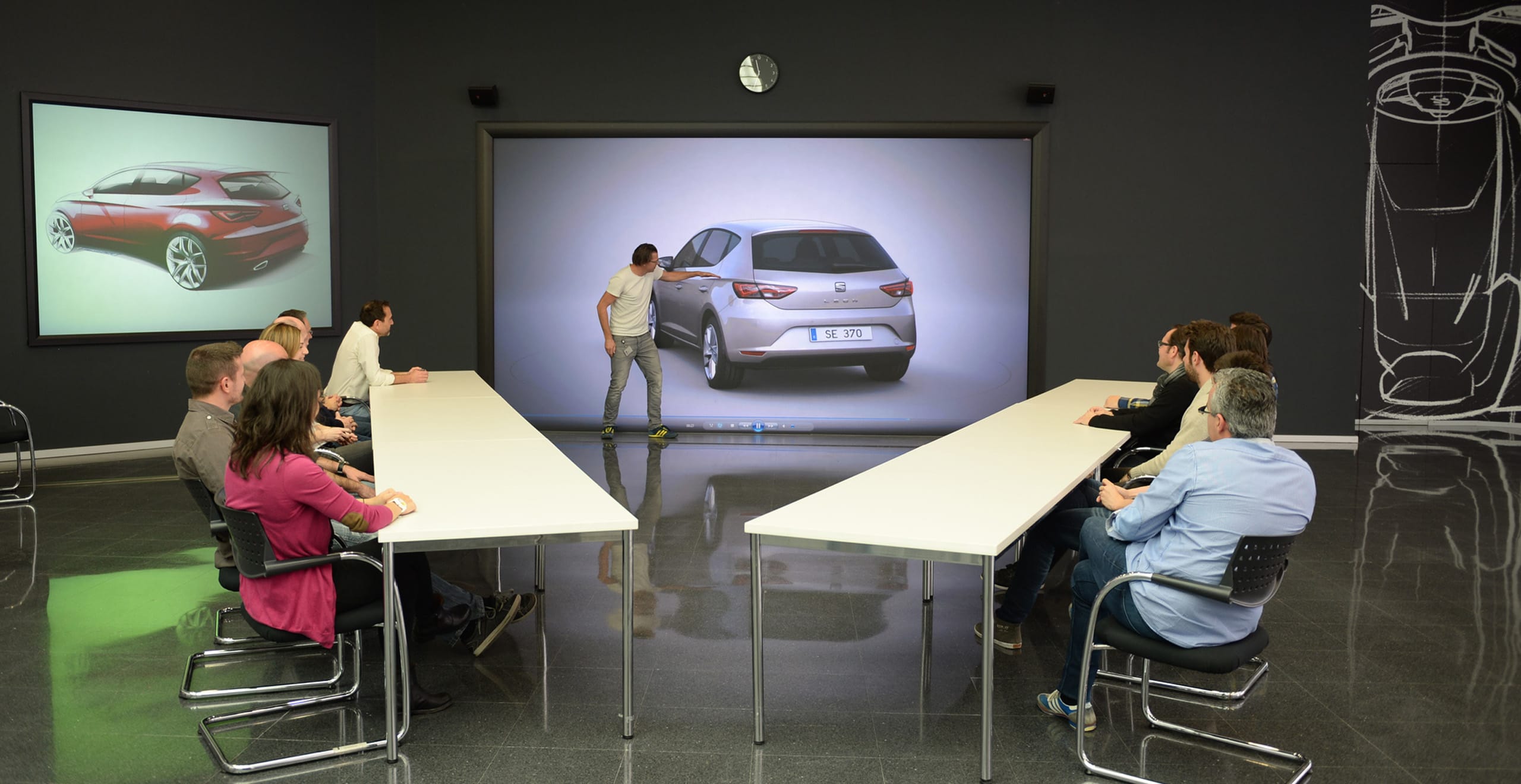 Roundtable discussion one man pointing at car design SEAT Leon with a group of people watching sitting at a table – SEAT Human Resources