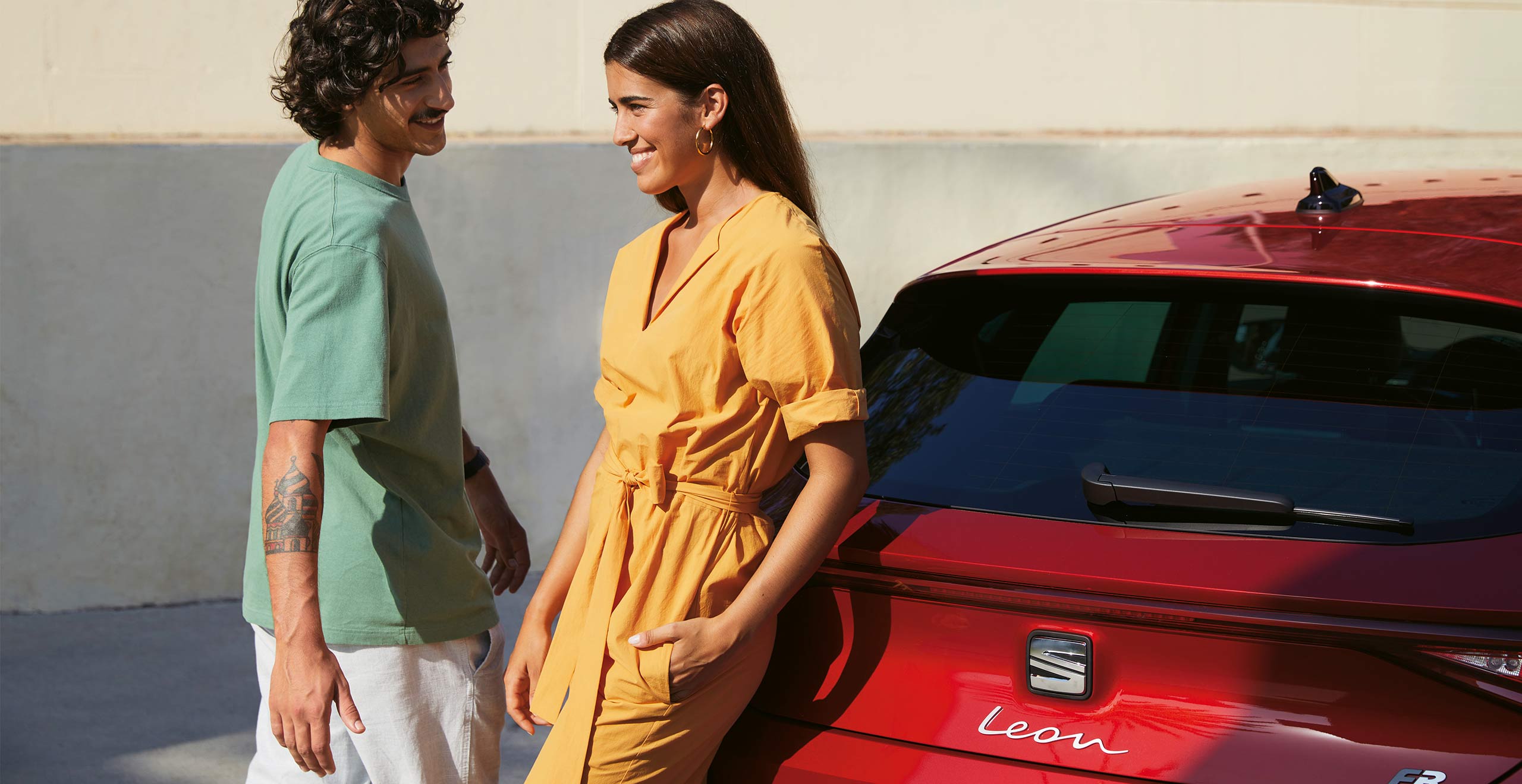 Couple talking next to a SEAT Leon desire red colour.