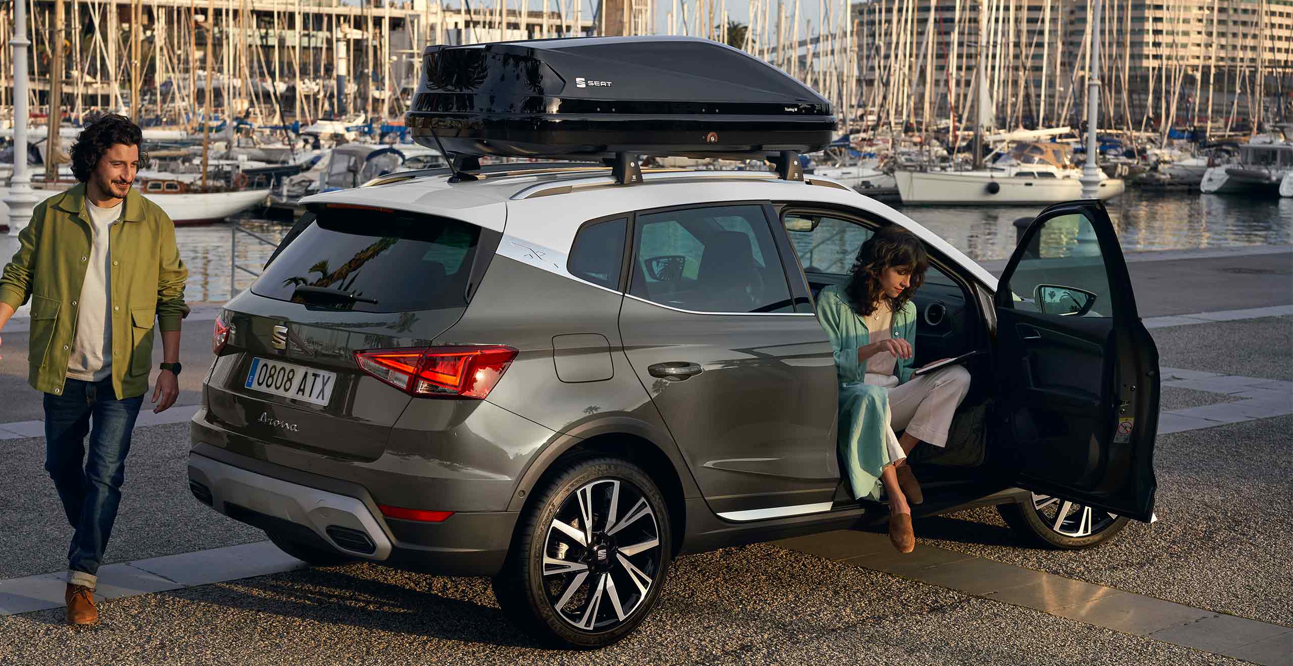 Woman sitting on SEAT Arona dark camouflage colour and white roof