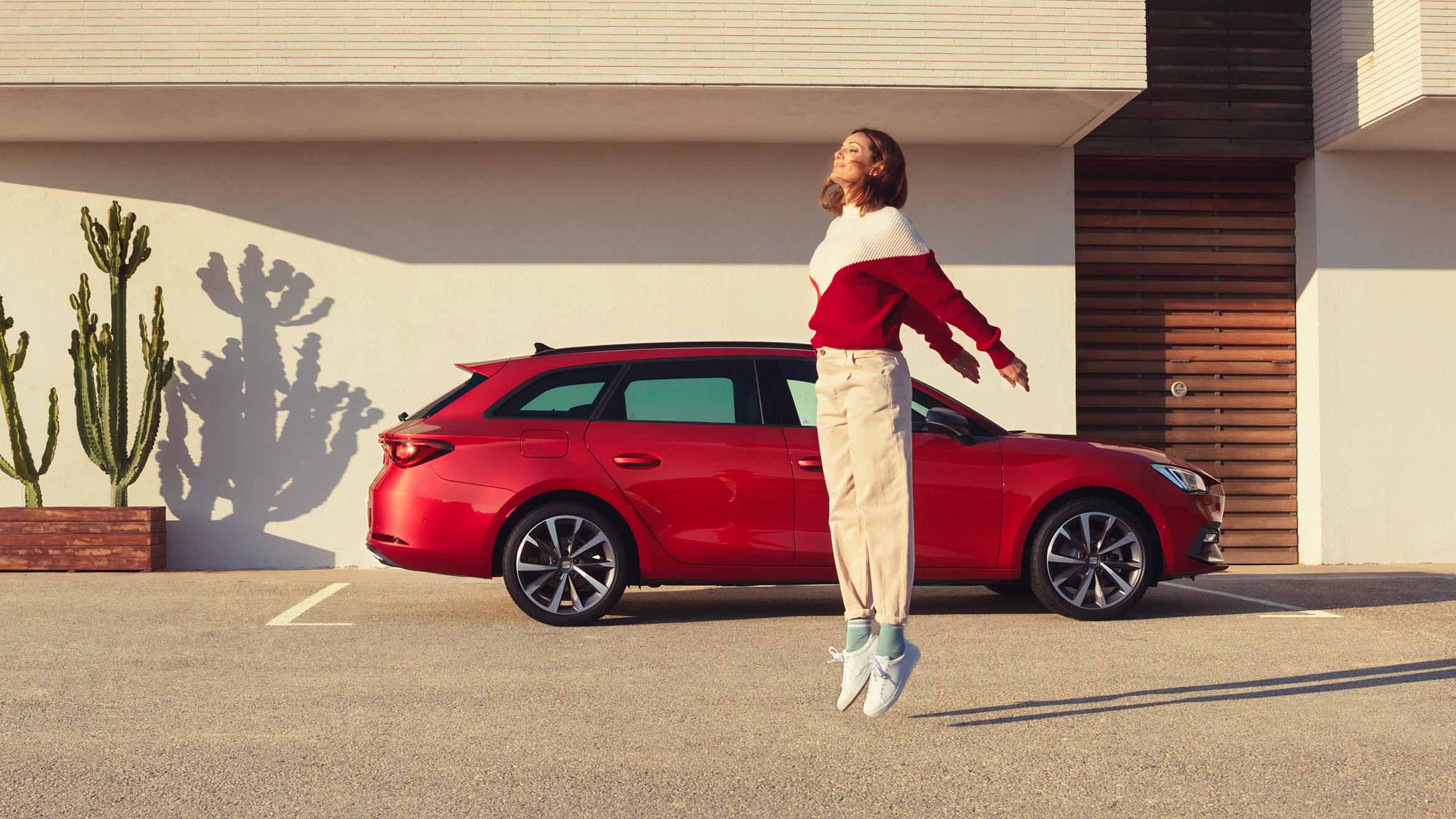  woman jumping next to seat leon sportstourer desire red colour.