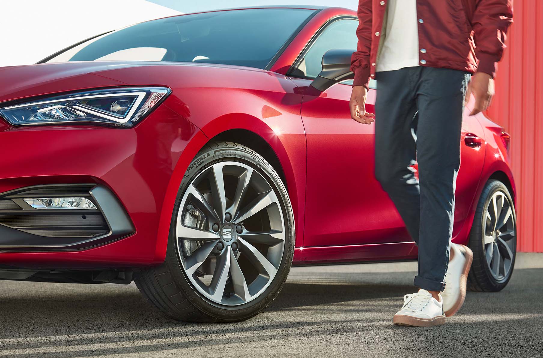 man standing next to seat leon desire red with cosmo grey alloy wheels
