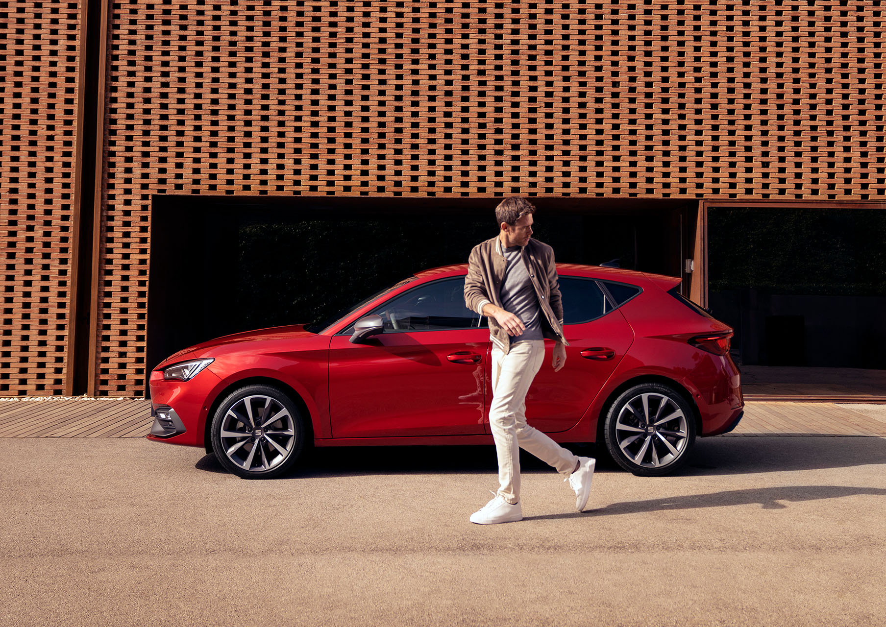 man walking next to SEAT Leon desire red colour with alloy wheels  