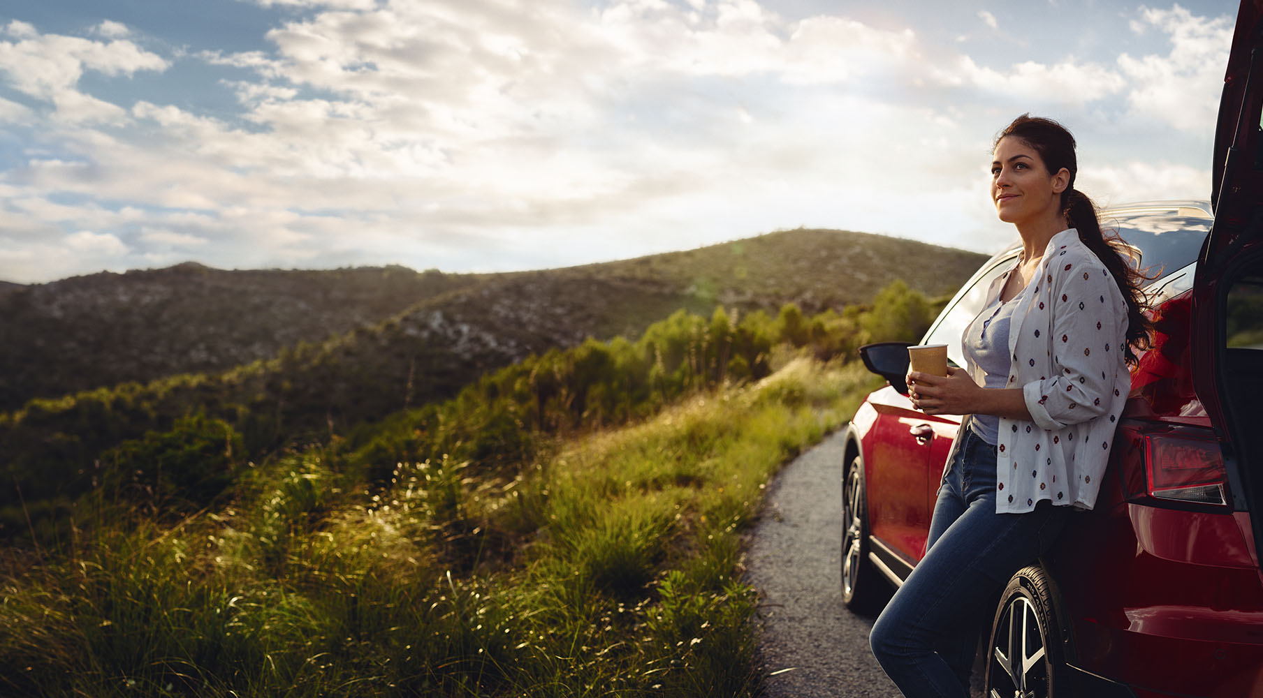 SEAT new car services maintenance end of life vehicles – Red SEAT Alhambra MPV 7 seater parked in countryside with grassy hills and a family standing beside