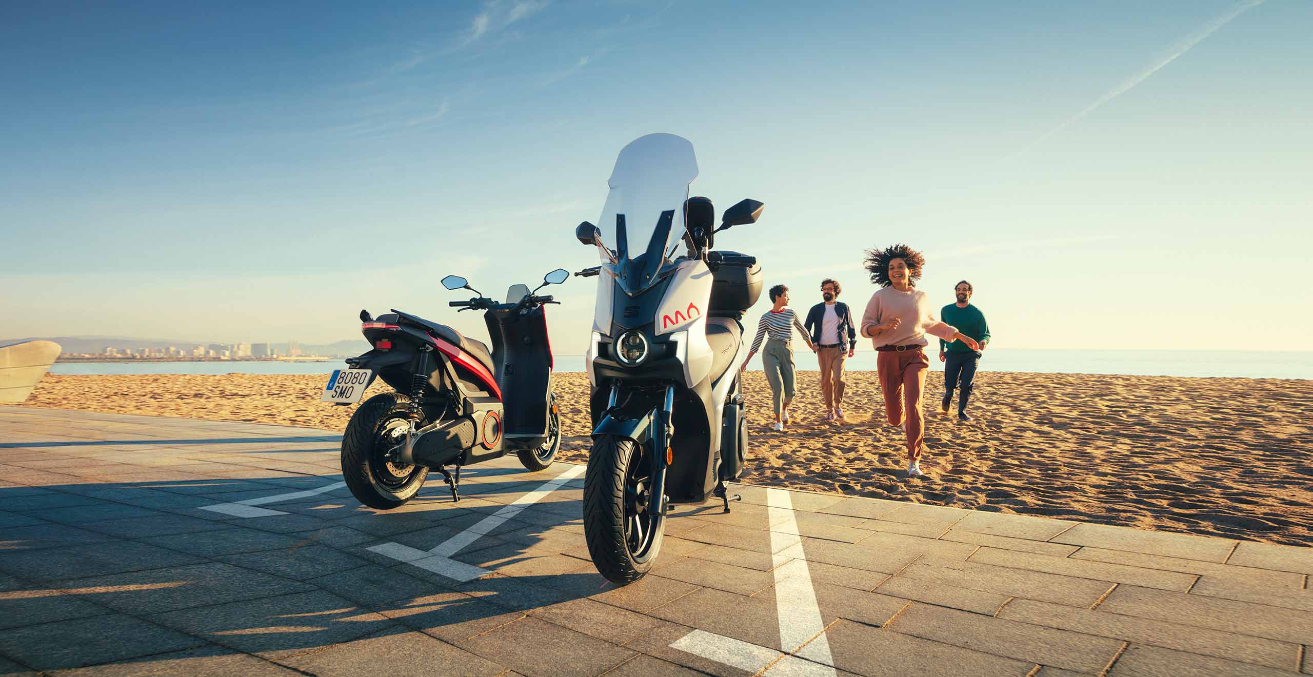Friends running to fully electric SEAT´s MÔ 125 daring red colour and dark aluminium colour. 