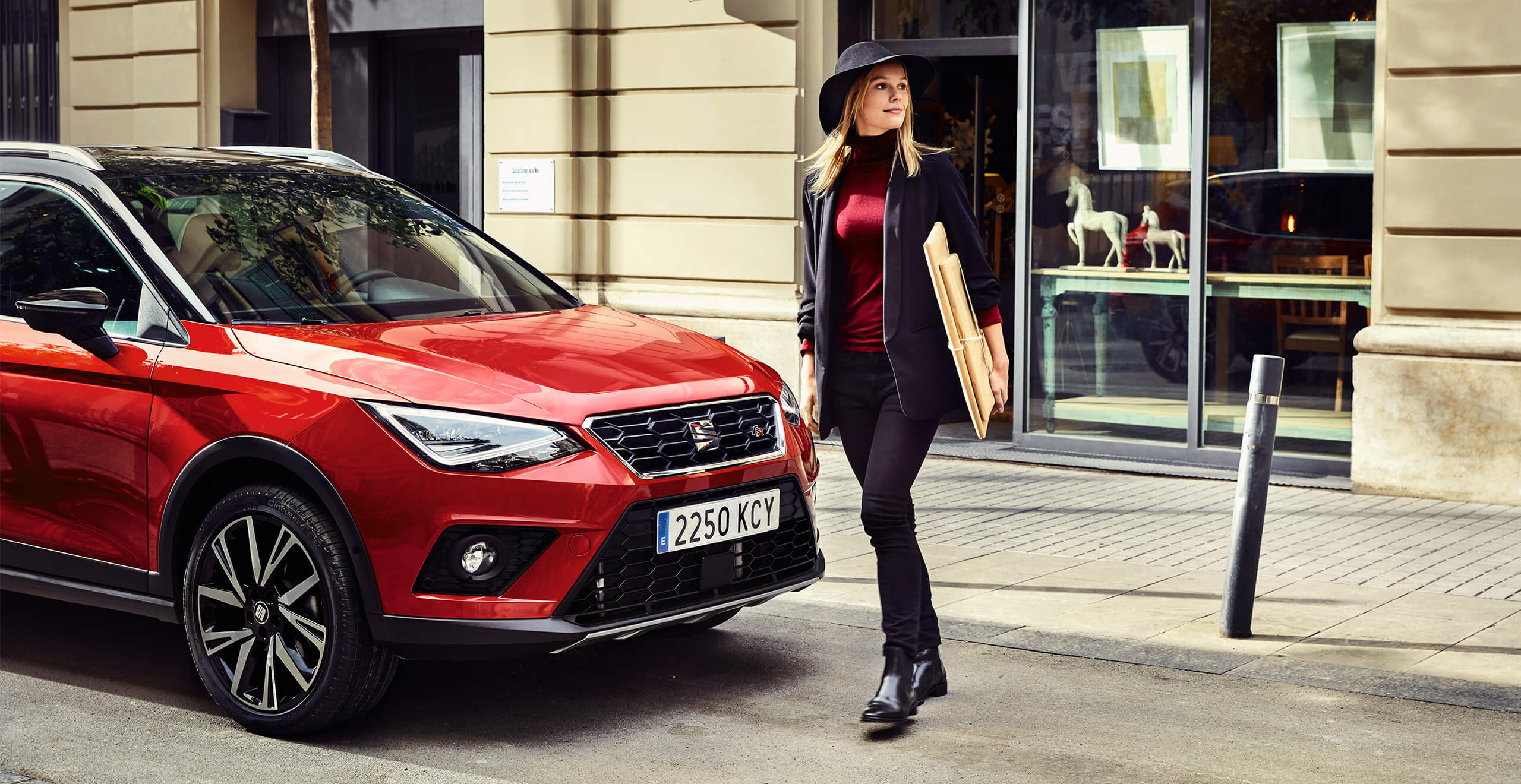 SEAT new car services and maintenance – Woman walking in front of a SEAT Arona crossover SUV